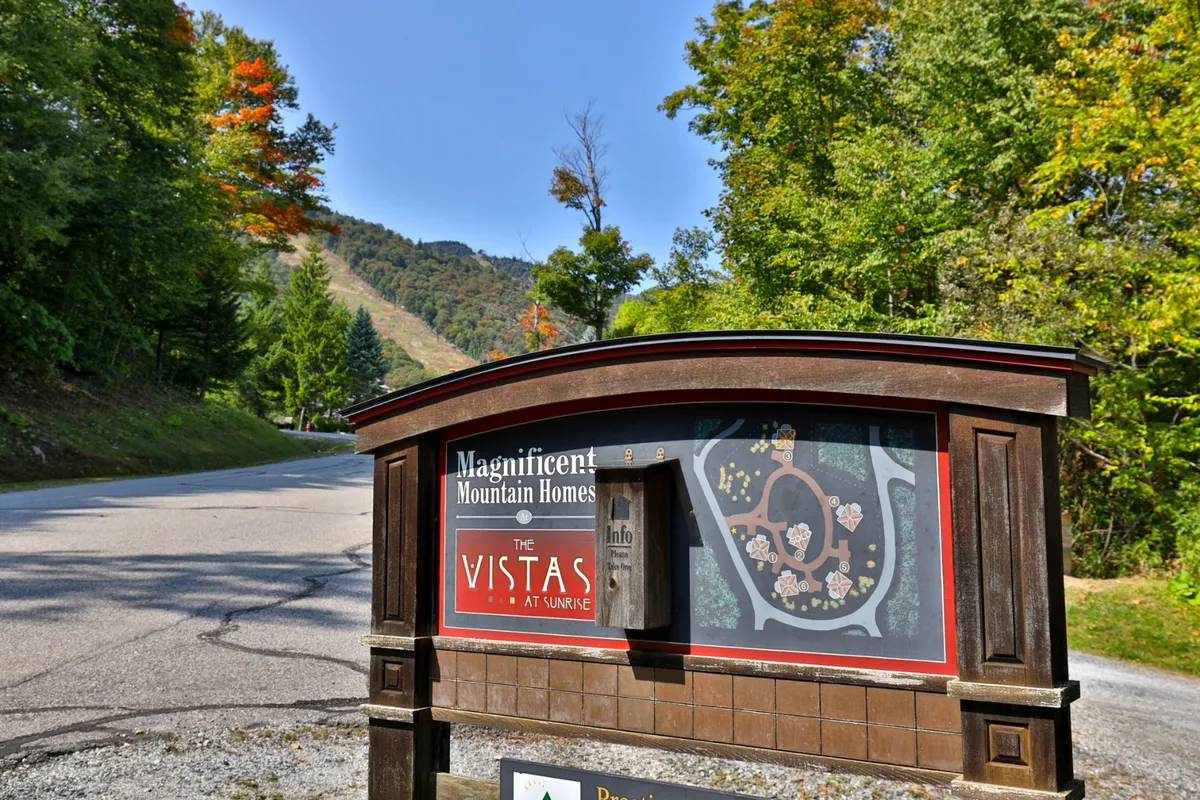 This image captures a serene mountain view with a prominent welcome sign and colorful autumn foliage, encapsulating the natural beauty and exploration opportunities just beyond the home.
